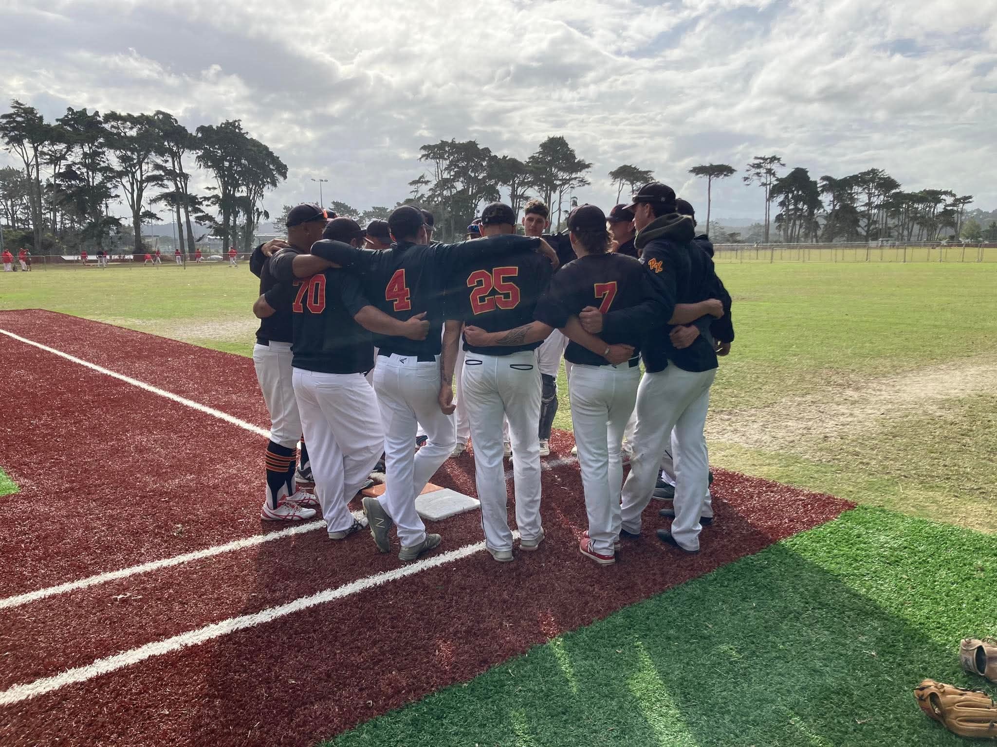 Players in a huddle on a softball pitch