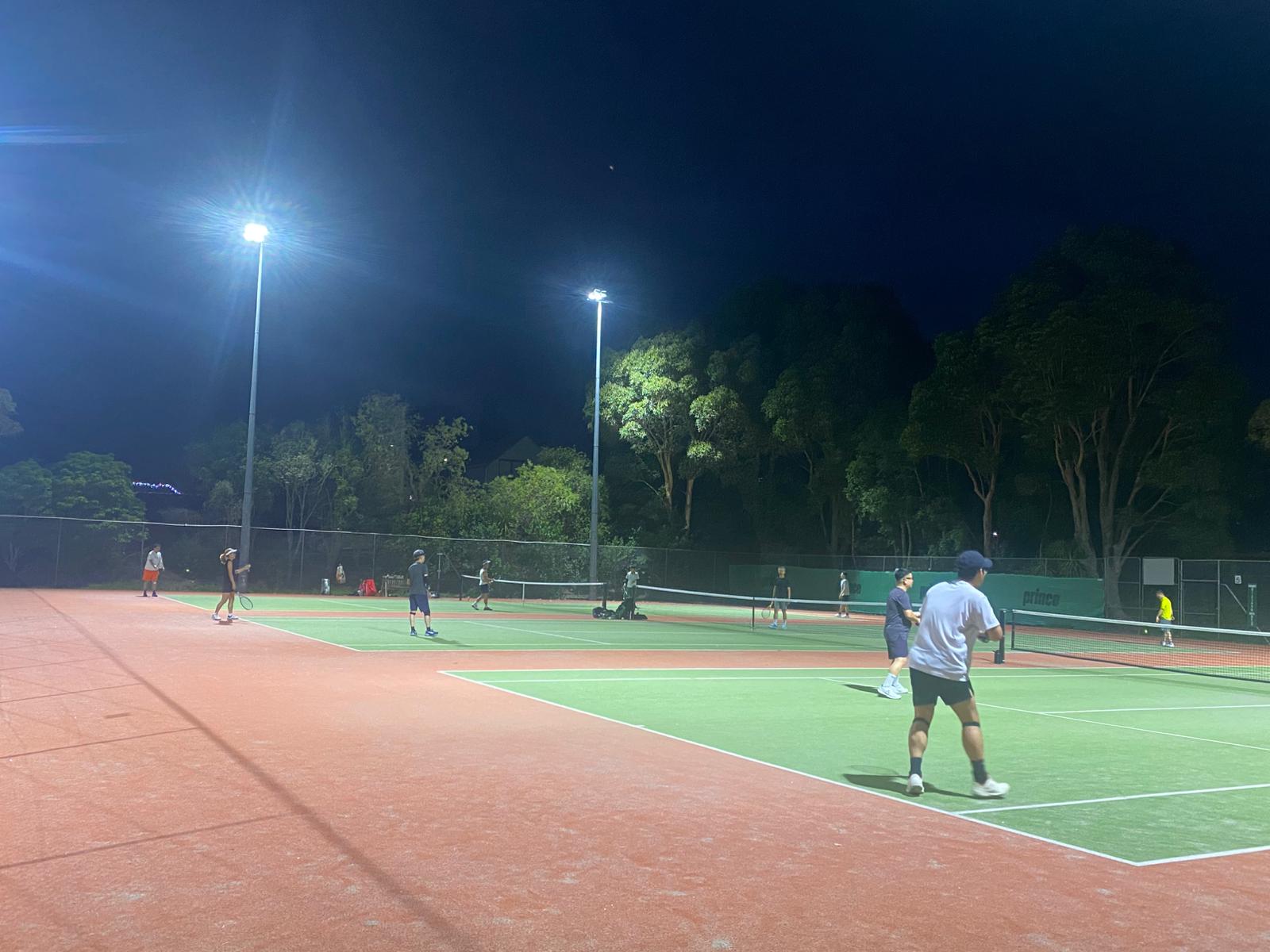 Players on a lit-up tennis court